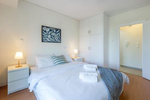 雅典Glyfada Center Sea View Apt的白色卧室配有一张白色大床和两盏灯