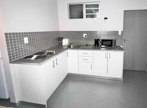 约翰内斯堡`Luxury Cosy City Apartment的小厨房配有白色橱柜和水槽