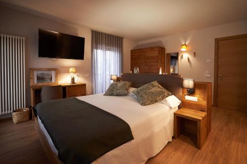 阿夏戈Hotel Ristorante Pennar的一间卧室配有一张大床和一台平面电视