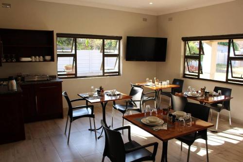 哈拉雷A pristine BB located in Belvedere Harare - 2006的用餐室设有桌椅和窗户。