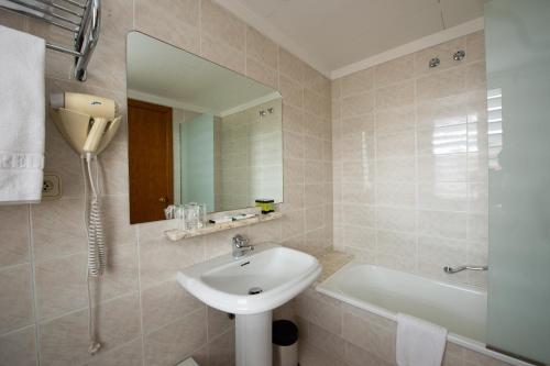 奥洛特博雷利酒店的一间带水槽、浴缸和镜子的浴室