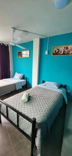 伊察La Casa de Bamboo的一间卧室设有两张床和蓝色的墙壁