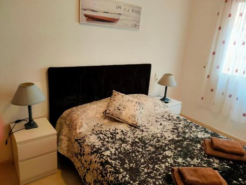 托雷维耶哈Casas Holiday - Playa del Cura的一间卧室配有一张带黑色床头板的床和两盏灯。