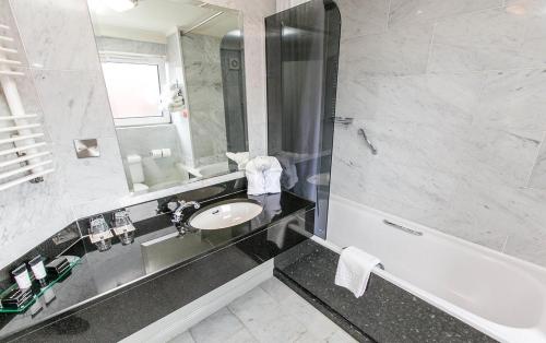 贝尔法斯特本尼迪克特酒店的一间带水槽、浴缸和镜子的浴室