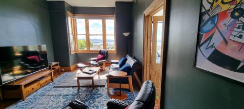 霍巴特Hill House Hobart - Charming home, stunning views close to city的带沙发和电视的客厅