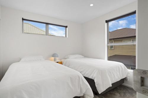 基督城Addington Delight - Christchurch Holiday Home的白色卧室设有两张床,配有窗户