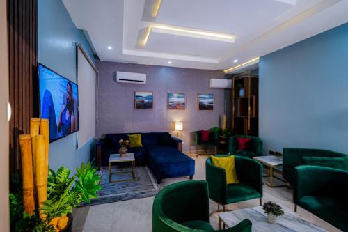 阿布贾Wali's Suites的客厅配有蓝色沙发和绿色椅子