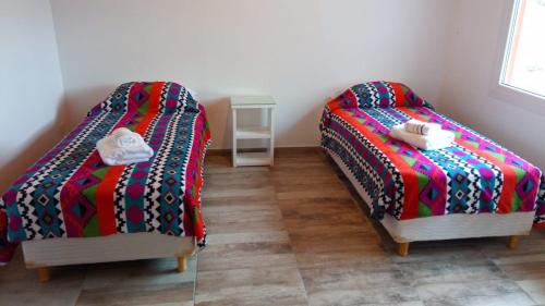 埃尔卡拉法特Apart Azul Calafate的两张睡床彼此相邻,位于一个房间里
