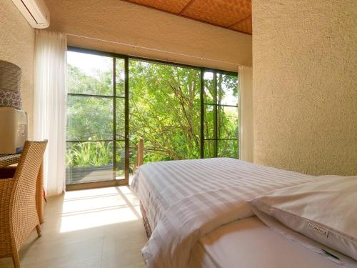 美娜多Thalassa Dive & Wellbeing Resort Manado的一间卧室设有一张床和一个大窗户