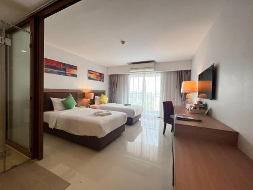 华欣Riche Hua Hin Hotel - SHA Plus的酒店客房设有两张床、一张桌子和一台电视。