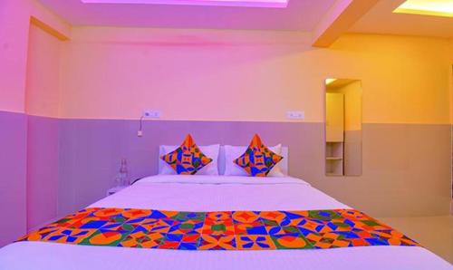 浦那FabHotel Empire Executive的一间卧室配有一张带色彩缤纷枕头的大床