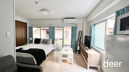 大阪Maison Milano Nakatsu Apartment的一间卧室配有一张床、一台电视和一张沙发