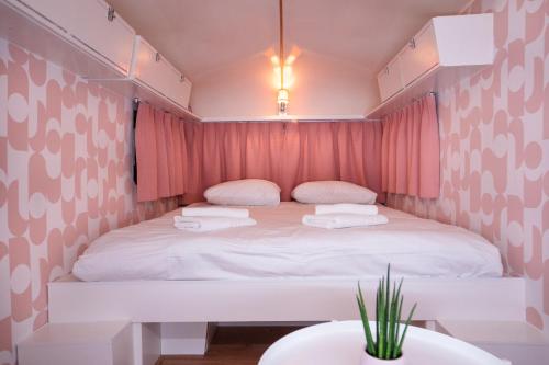阿姆斯特丹Outside Inn的一间小卧室,配有白色的床和粉红色窗帘