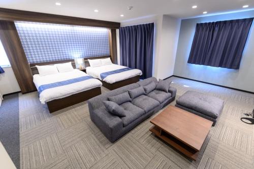 东京Sugamo Winco Residence的酒店客房,设有两张床和一张沙发