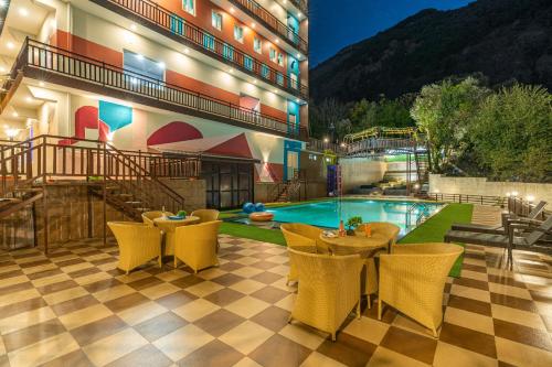 达兰萨拉Zostel Plus Kareri的酒店设有一个游泳池和桌椅