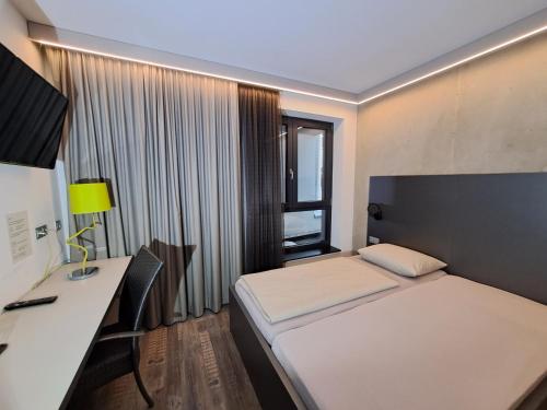 耶拿Hotel Eulensteins的配有一张床、一张书桌和一扇窗户的酒店客房