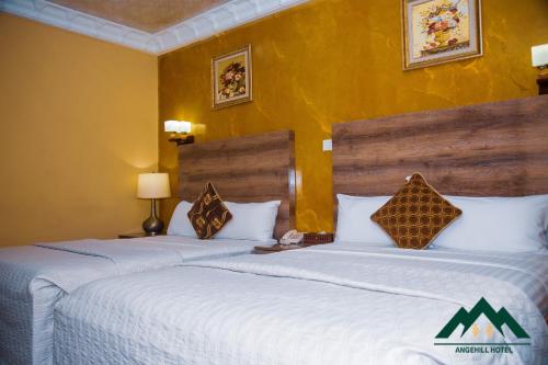阿克拉Ange Hill Hotel的两张床位于带黄色墙壁的酒店客房