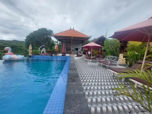 珀尼达岛Innora Jungle Resort And Spa的一座带遮阳伞的别墅旁的游泳池
