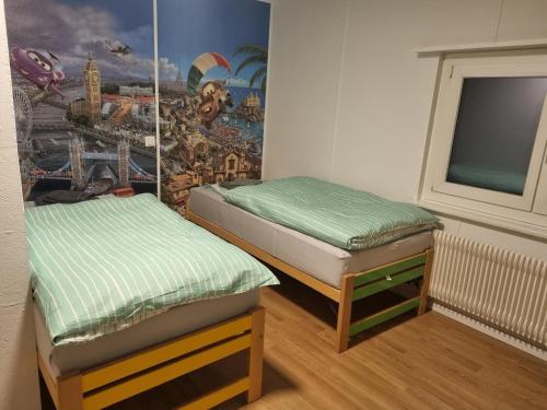 Sennwald24-7 Rooms的墙上壁画的房间里设有两张床