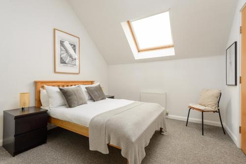 爱丁堡The Modern Mill Apartment的一间卧室设有一张床、一个窗口和一把椅子