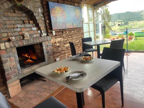 苏埃斯卡Glamping Naturaleza - mirador de la laguna de suesca的带壁炉的客房内的桌椅