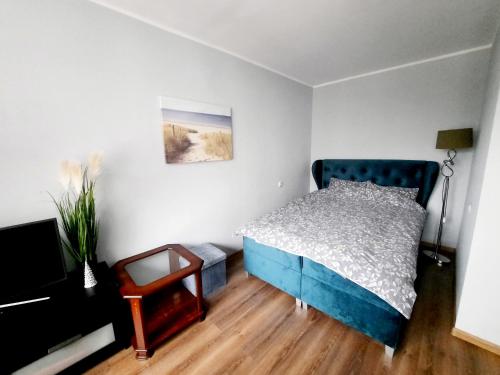 里加Light Apartment的一间卧室设有蓝色的床,铺有木地板。