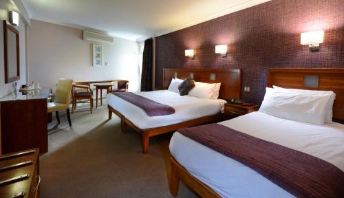 戈尔韦戈尔韦皇家酒店的酒店客房设有两张床和一张桌子。