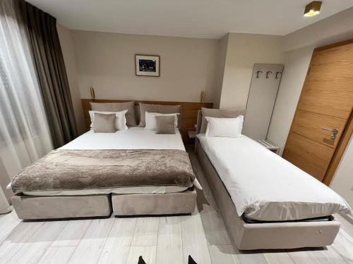 卢森堡Albergo Aida的配有白色床单的酒店客房内的两张床
