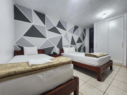 皮乌拉Hotel Villa del Sol的一间带两张床的卧室和几何墙