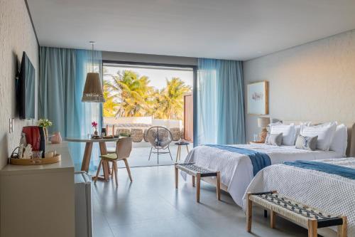 泰巴Saline Taíba Boutique Beach Hotel的酒店客房带两张床和一张桌子以及椅子。