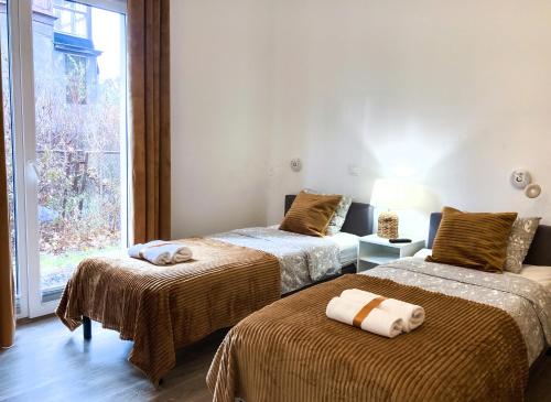 索波特Chummy House Sopot的客房设有两张带棕色毯子的床和窗户。
