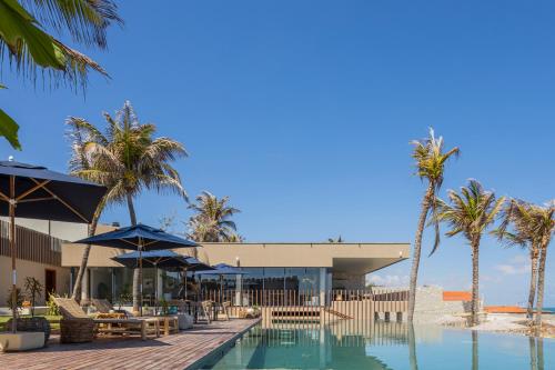 泰巴Saline Taíba Boutique Beach Hotel的一个带游泳池和棕榈树的度假村