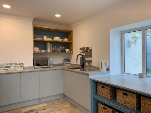 圣艾夫斯Treloyhan Lodge的厨房配有白色橱柜、水槽和窗户。