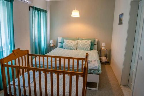 EstanqueiroQuinta dos Pinheiros的一间卧室配有一张带蓝色窗帘的床和一张婴儿床。