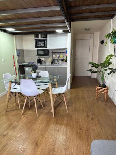 蒙得维的亚Mapar Studio en Montevideo的一间设有玻璃桌和白色椅子的用餐室