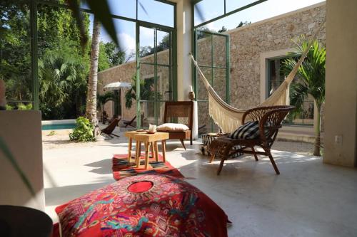梅里达Nuik Casa Tropical的带吊床和椅子的门廊以及带窗户的客房。