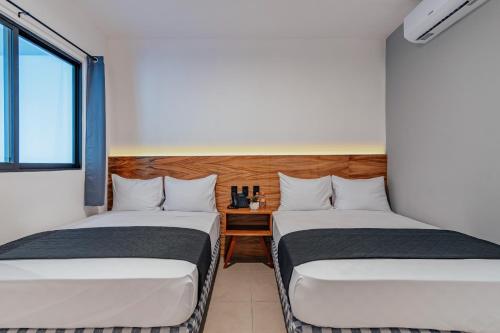梅里达Hotel Mody Merida的带窗户的客房内设有两张单人床。