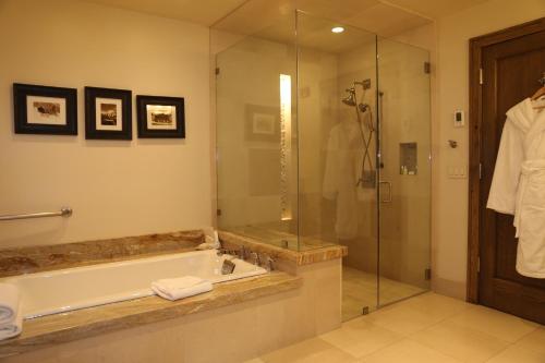 帕克城Deluxe Two Queen Room with Fireplace Hotel Room的带浴缸和玻璃淋浴间的浴室。