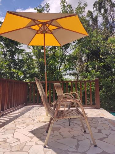 伊塔乌纳斯Pousada Aroeira的庭院配有两把椅子和一把遮阳伞