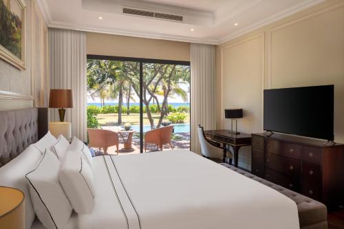 金兰Meliá Vinpearl Cam Ranh Beach Resort的一间卧室配有一张大床和电视