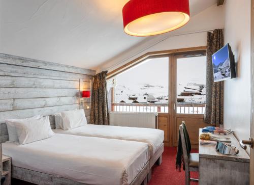 蒂涅Hôtel L'Aiguille Percée的酒店客房设有两张床和窗户。