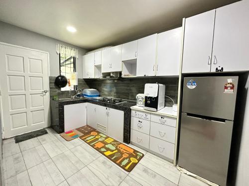 仙本那ANG LEE HOLIDAY HOME 1的厨房配有白色橱柜和不锈钢冰箱