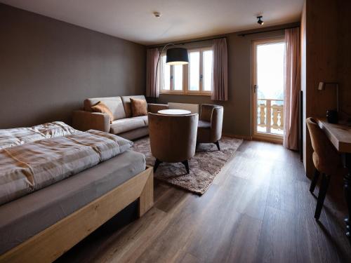 贝特默阿尔卑全景餐厅酒店 的一间卧室配有一张床、一张沙发和一张桌子