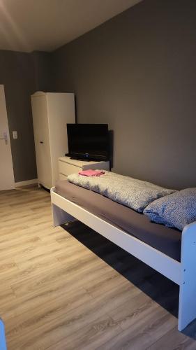 弗伦斯堡Flensburg Strandnah的一间卧室配有一张床和一个带冰箱的梳妆台