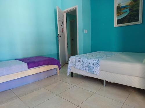 萨尔瓦多Diversão, churrasco e piscina - Praia de Ipitanga的蓝色墙壁客房的两张床