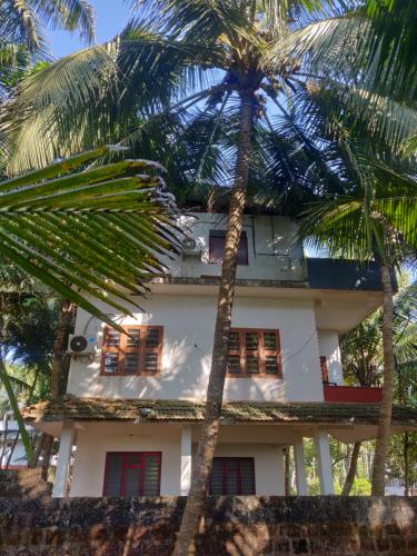 坎努尔Sunshine Service Villa的一座棕榈树掩映的白色房子