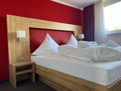 普里茨瓦尔克Hotel Ziegenkrug - Pritzwalk的一间卧室设有一张红色墙壁的大床