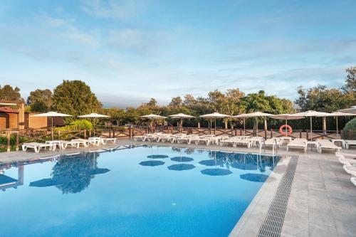 罗萨斯Hotel Mediterraneo的度假村的游泳池配有椅子和遮阳伞