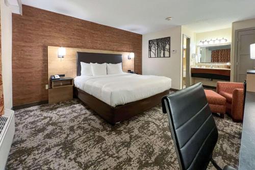 奥古斯塔Maine Evergreen Hotel, Ascend Hotel Collection的配有一张床和一把椅子的酒店客房