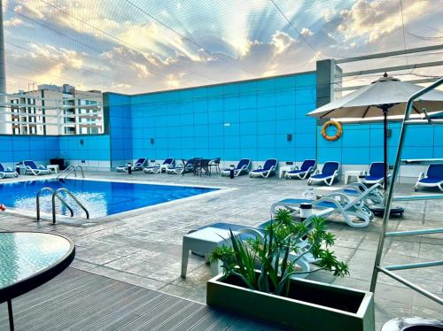 沙迦沙迦国敦大酒店的一座带椅子和遮阳伞的大楼的顶部游泳池